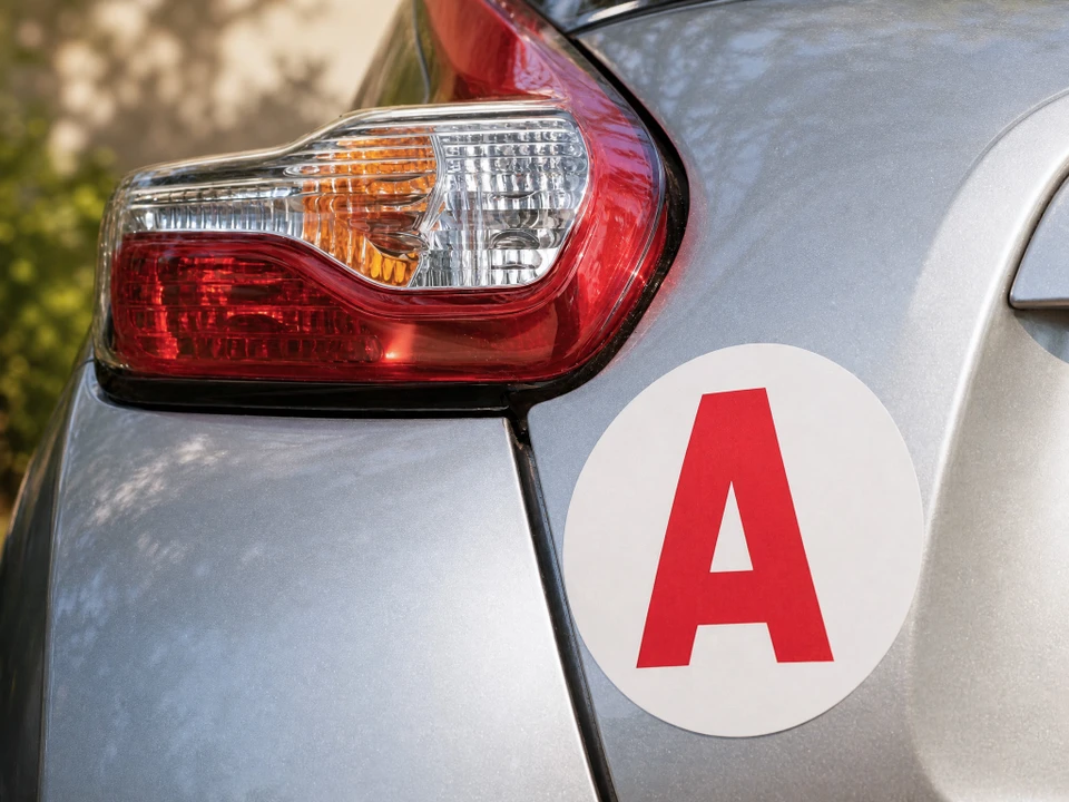 Véhicules d'auto-école garés en extérieur, signalés par des panneaux lumineux rouges "AUTO-ÉCOLE"