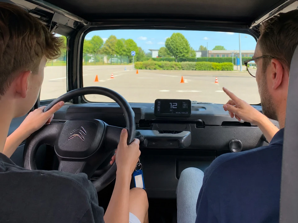 Piste d'entraînement extérieure balisée avec des cônes de signalisation bleus et orange, des jalons verticaux oranges sur socles et des cônes rouges et blancs